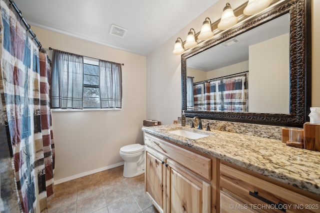 bathroom with toilet, vanity, and tile patterned flooring