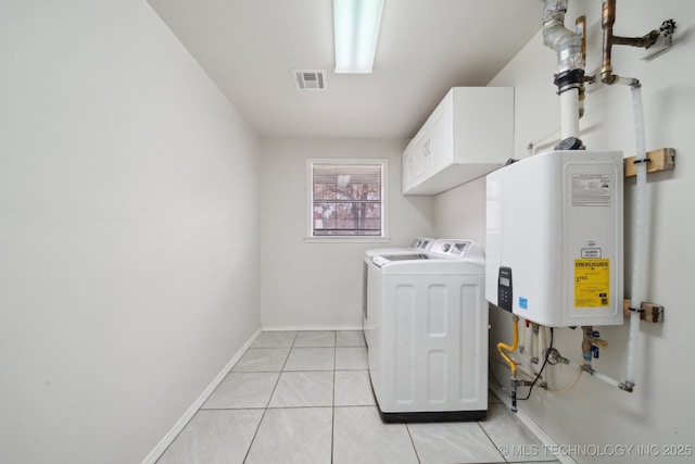 laundry room featuring light tile patterned floors, water heater, washing machine and dryer, and cabinets