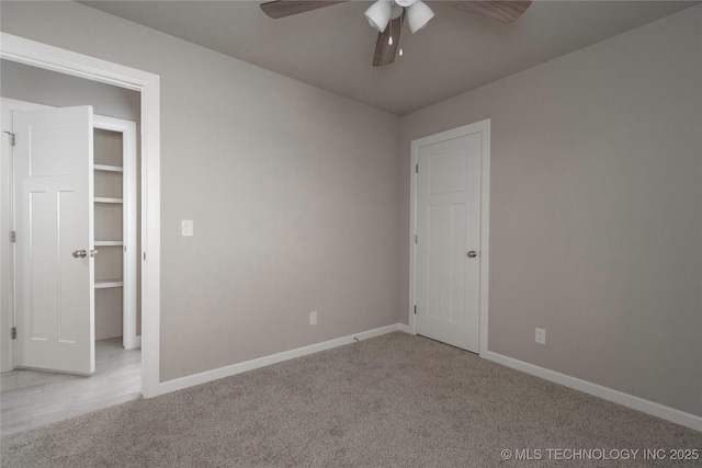 unfurnished bedroom featuring light carpet, ceiling fan, a walk in closet, and a closet