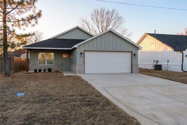 view of front of property featuring a garage, a front lawn, and central AC