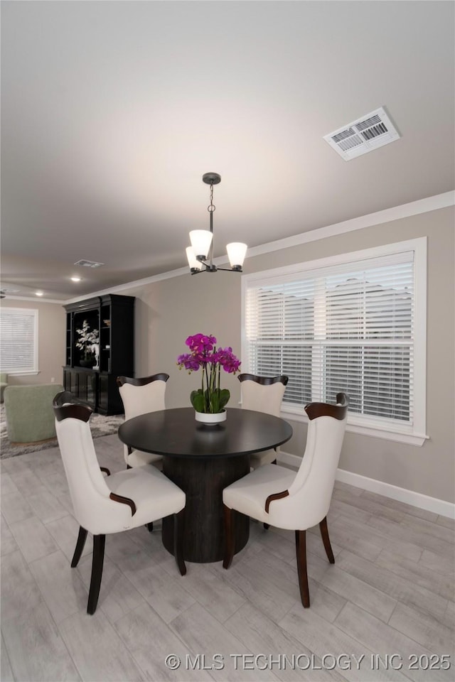 dining room featuring light wood-type flooring, a notable chandelier, and ornamental molding