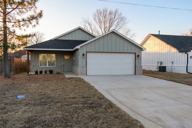 view of front facade featuring a garage, a front yard, and central air condition unit