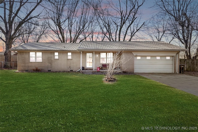 ranch-style home featuring a garage and a yard