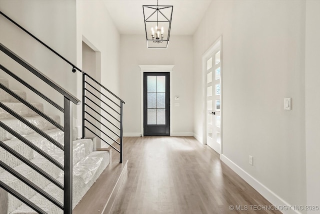 entrance foyer featuring stairs, an inviting chandelier, wood finished floors, and baseboards