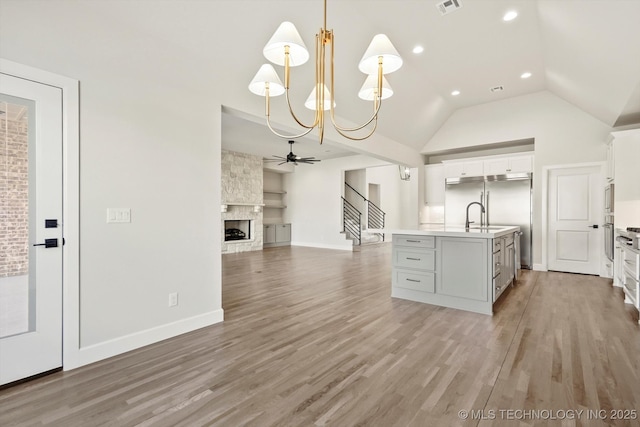 kitchen with lofted ceiling, light countertops, a large fireplace, open floor plan, and light wood-type flooring