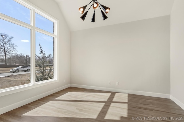 spare room featuring vaulted ceiling, wood finished floors, and baseboards