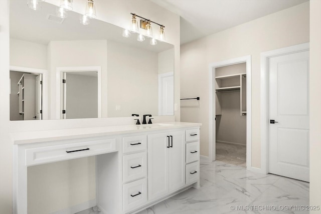 full bathroom featuring visible vents, vanity, baseboards, marble finish floor, and a walk in closet