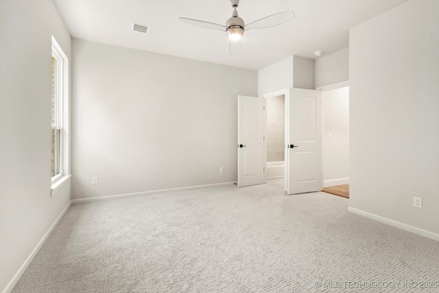 empty room with ceiling fan, visible vents, baseboards, and light colored carpet