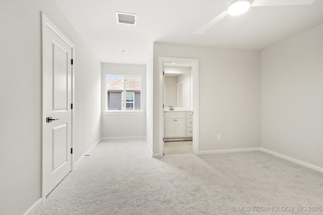 unfurnished bedroom with baseboards, visible vents, connected bathroom, and light colored carpet