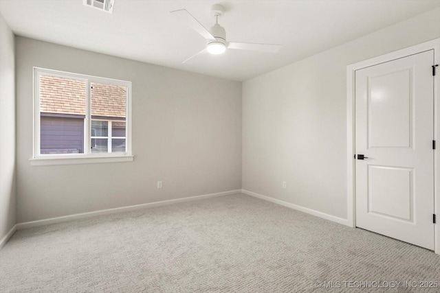 carpeted spare room featuring visible vents, ceiling fan, and baseboards