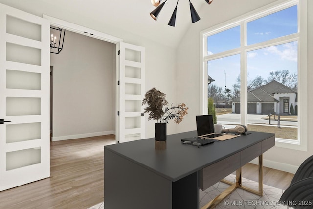 home office with built in shelves, lofted ceiling, wood finished floors, baseboards, and ceiling fan with notable chandelier