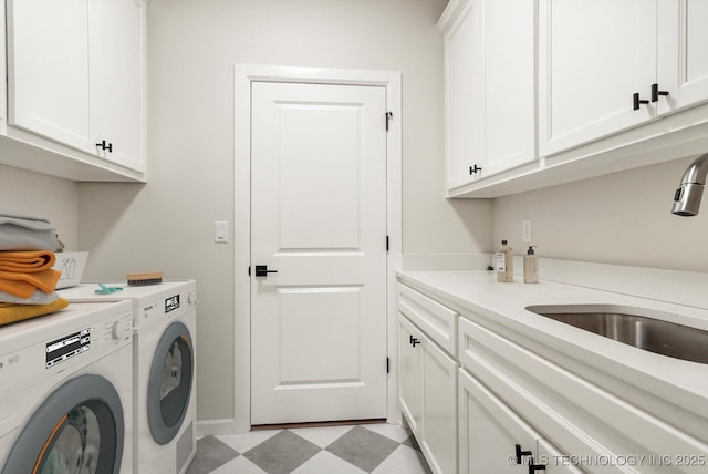 laundry area featuring washer and dryer, cabinet space, a sink, and light floors