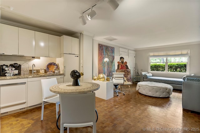 interior space featuring track lighting, white cabinetry, white refrigerator, sink, and ornamental molding