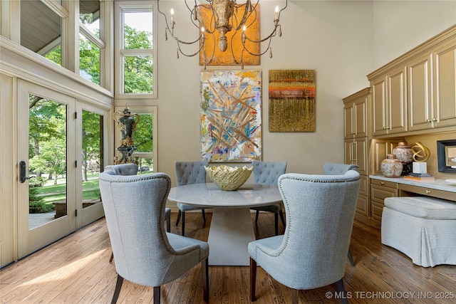 dining space featuring an inviting chandelier, a high ceiling, and light hardwood / wood-style floors