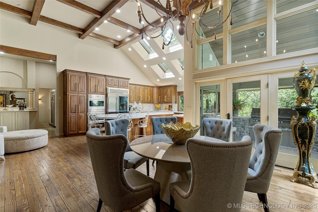 dining space with a chandelier, french doors, a towering ceiling, and light wood-type flooring