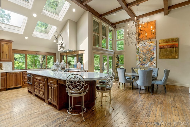 kitchen featuring a skylight, a breakfast bar area, decorative light fixtures, light wood-type flooring, and a center island