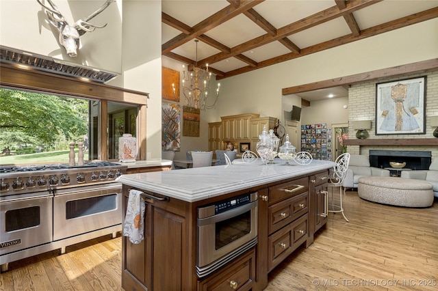 kitchen featuring dark brown cabinetry, an inviting chandelier, double oven range, light wood-type flooring, and coffered ceiling