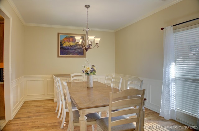 dining area featuring light wood-type flooring, ornamental molding, and an inviting chandelier