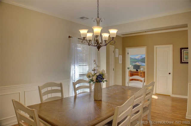 dining area featuring a chandelier, light wood-type flooring, and ornamental molding