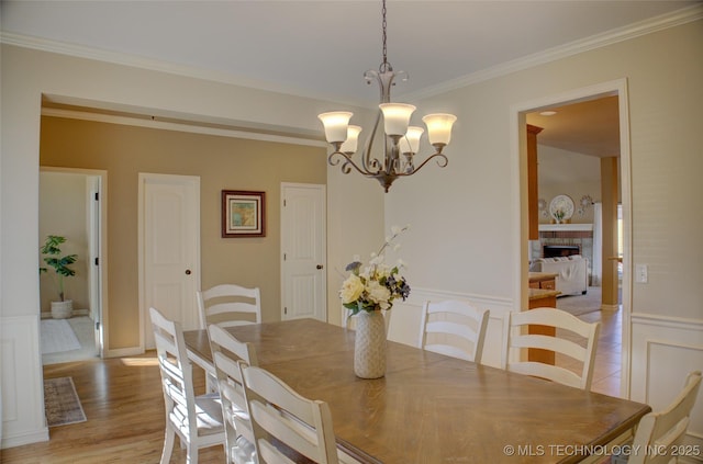 dining area with light hardwood / wood-style floors, ornamental molding, and a notable chandelier