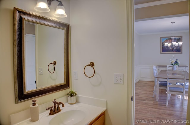 bathroom with vanity, a notable chandelier, ornamental molding, and hardwood / wood-style floors