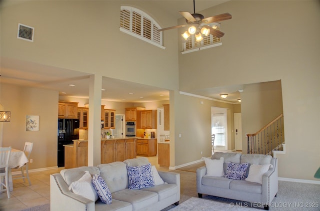 living room with ceiling fan, a towering ceiling, and light tile patterned flooring