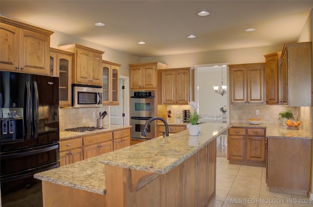 kitchen featuring decorative light fixtures, an island with sink, tasteful backsplash, and stainless steel appliances