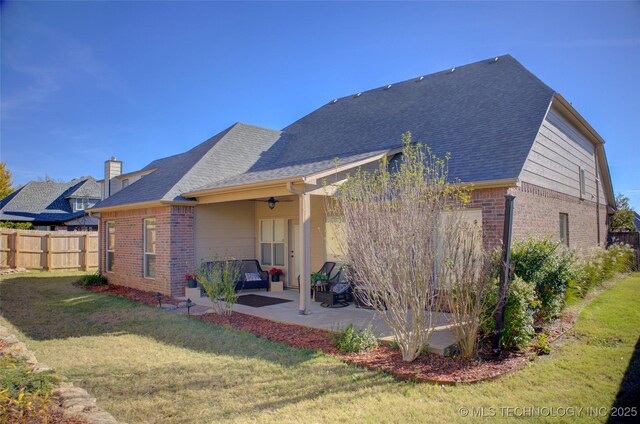 rear view of house with ceiling fan, a patio area, and a yard