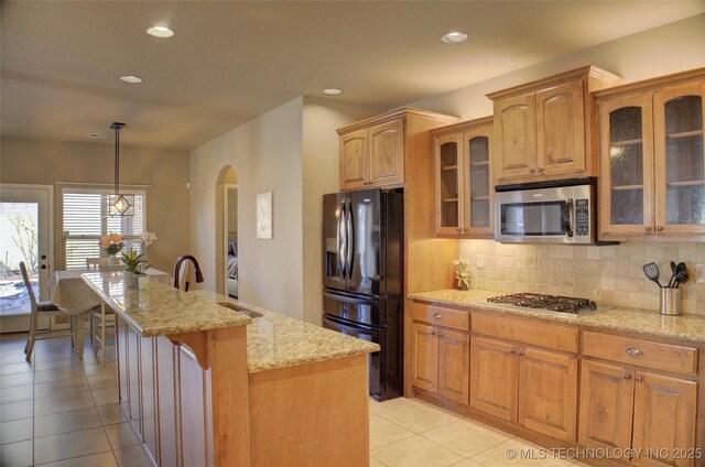 kitchen with decorative light fixtures, backsplash, a center island, light stone countertops, and stainless steel appliances