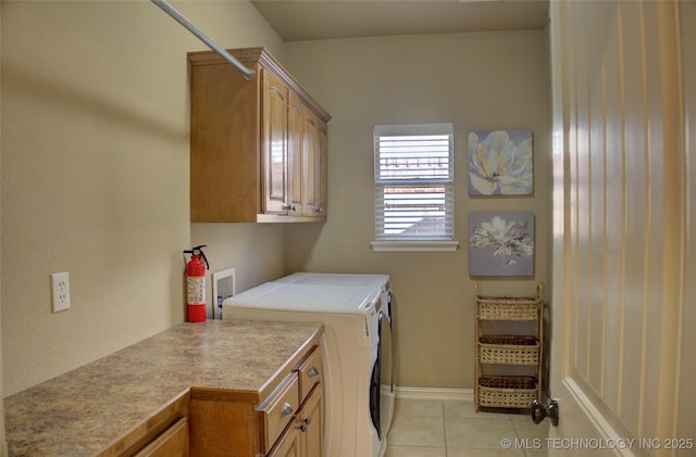 laundry area featuring washer and dryer, cabinets, and light tile patterned floors