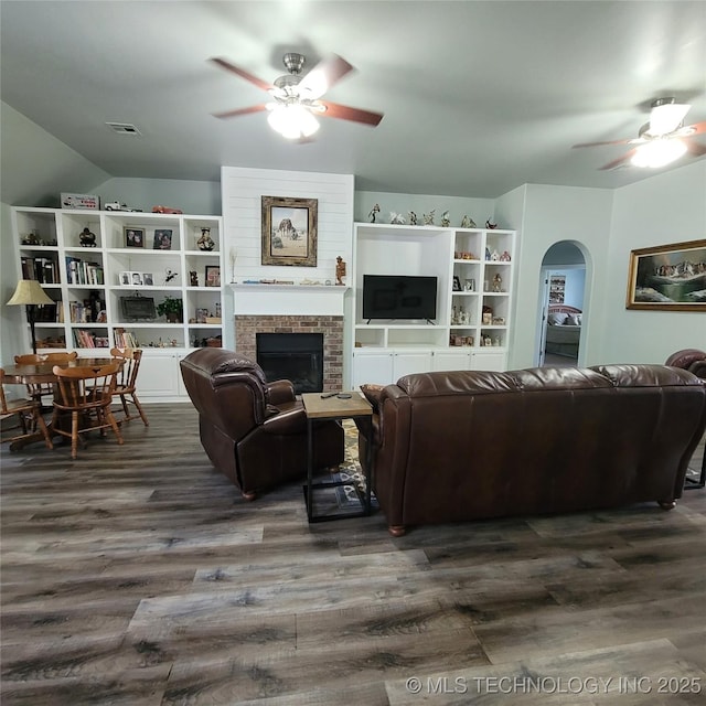 living room featuring dark wood-type flooring, ceiling fan, a fireplace, and lofted ceiling