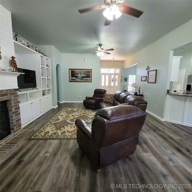 living room featuring a brick fireplace, dark hardwood / wood-style flooring, and ceiling fan