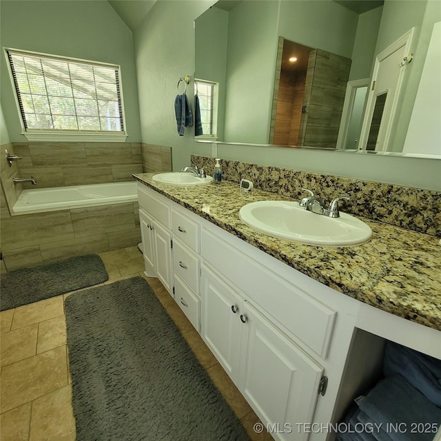 bathroom featuring vaulted ceiling, tile patterned floors, tiled tub, and vanity