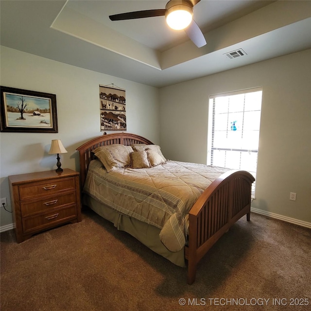 carpeted bedroom featuring ceiling fan and a raised ceiling