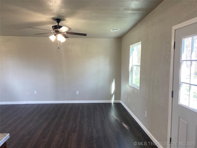 empty room with a textured ceiling, ceiling fan, and dark hardwood / wood-style floors