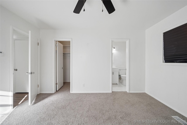 unfurnished bedroom featuring a spacious closet, light carpet, ceiling fan, ensuite bath, and a closet