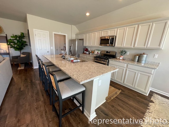 kitchen featuring a kitchen breakfast bar, white cabinets, a center island with sink, and stainless steel appliances