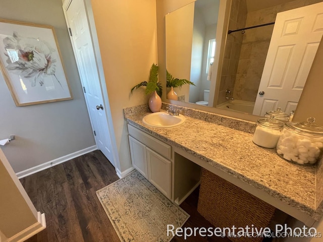 full bathroom featuring toilet, tiled shower / bath combo, vanity, and hardwood / wood-style floors