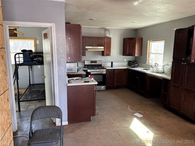 kitchen with a healthy amount of sunlight, stainless steel gas stove, sink, and a textured ceiling