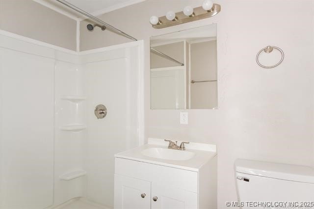 bathroom featuring toilet, a shower, and vanity