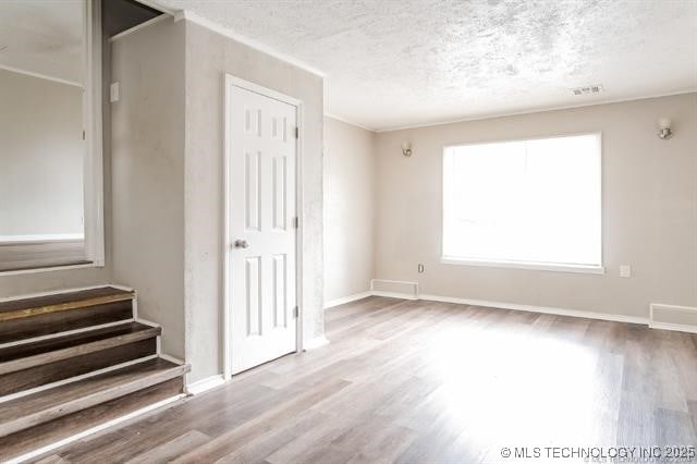 empty room featuring a textured ceiling and light hardwood / wood-style flooring