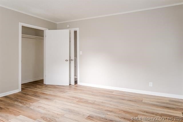 unfurnished bedroom with a closet, ornamental molding, and light hardwood / wood-style flooring