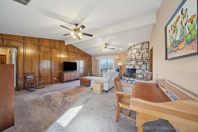 carpeted living room featuring vaulted ceiling, ceiling fan, a fireplace, and wood walls