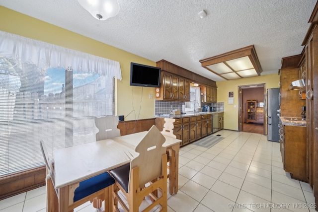 dining area with light tile patterned floors, sink, a textured ceiling, and a wealth of natural light