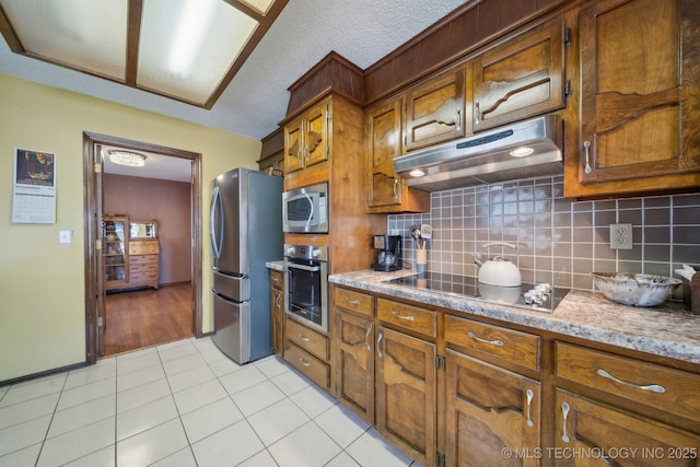 kitchen with appliances with stainless steel finishes, light tile patterned floors, and decorative backsplash