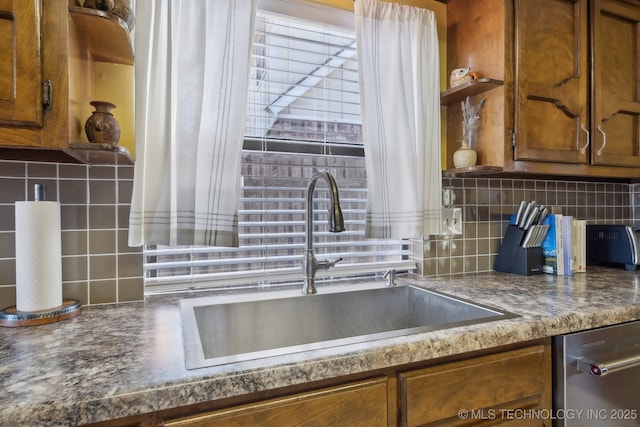 kitchen featuring stainless steel dishwasher, sink, and decorative backsplash