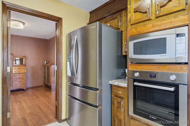 kitchen featuring light hardwood / wood-style flooring, stainless steel appliances, and a textured ceiling