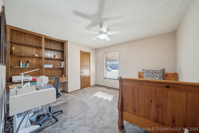 office area featuring light carpet, ceiling fan, and a textured ceiling