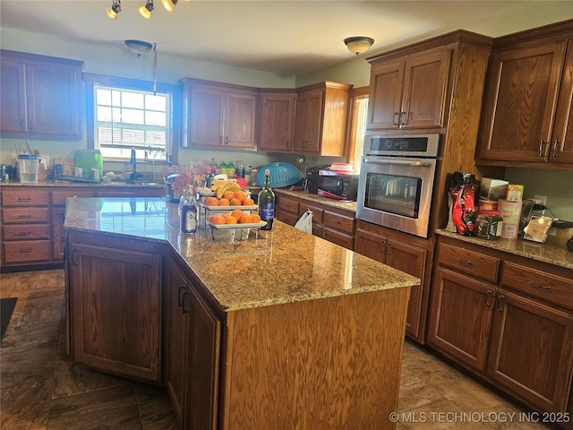 kitchen featuring decorative light fixtures, oven, a kitchen island, dark tile patterned floors, and light stone countertops