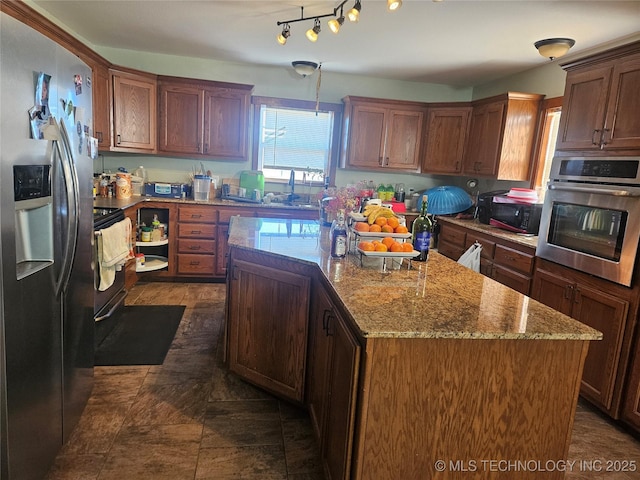 kitchen featuring stainless steel appliances, light stone countertops, hanging light fixtures, and a kitchen island